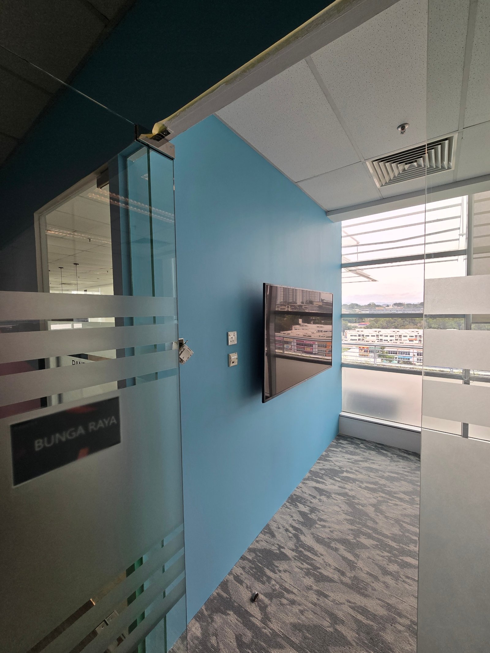 Bunga Raya meeting room at Nasstar Cyberjaya with blue painted wall and wall-mounted TV