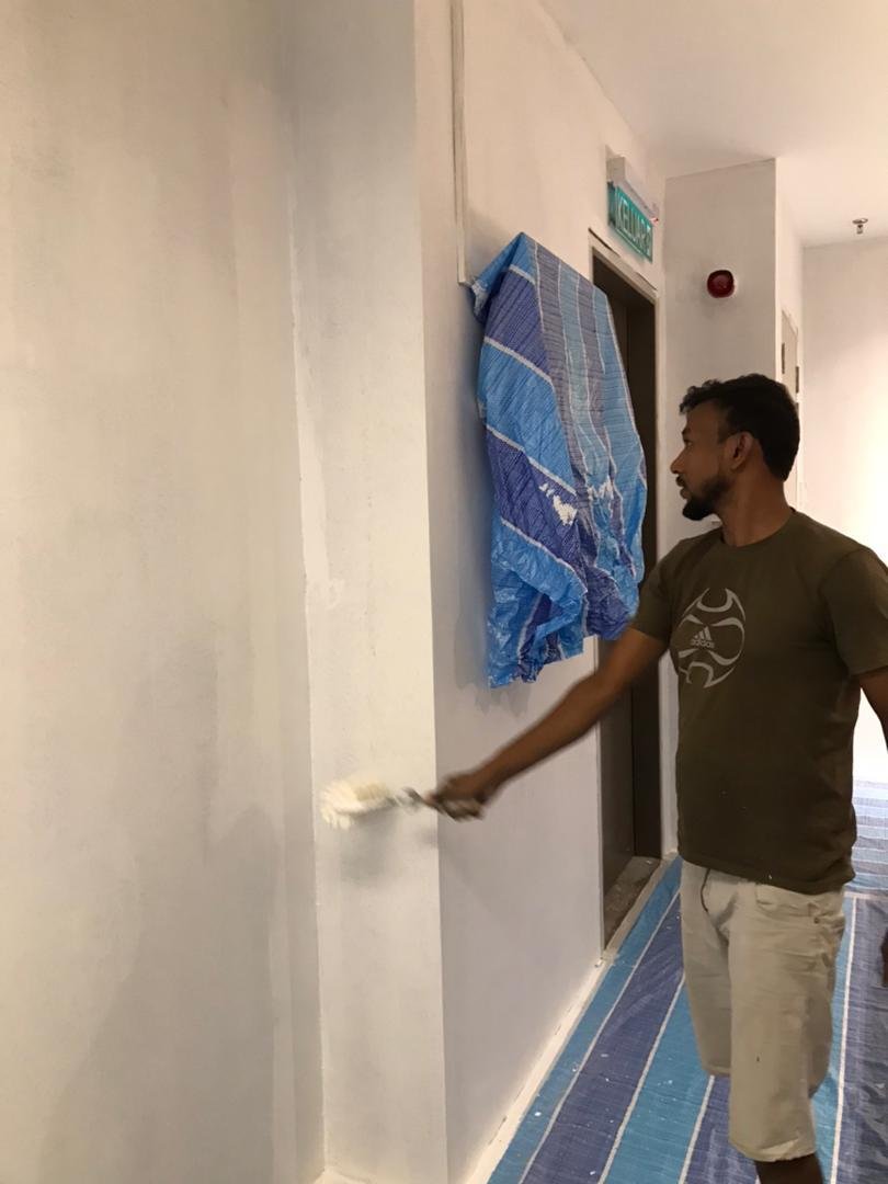Painter applying white paint to corridor wall at KLEM Clinics healthcare fit-out