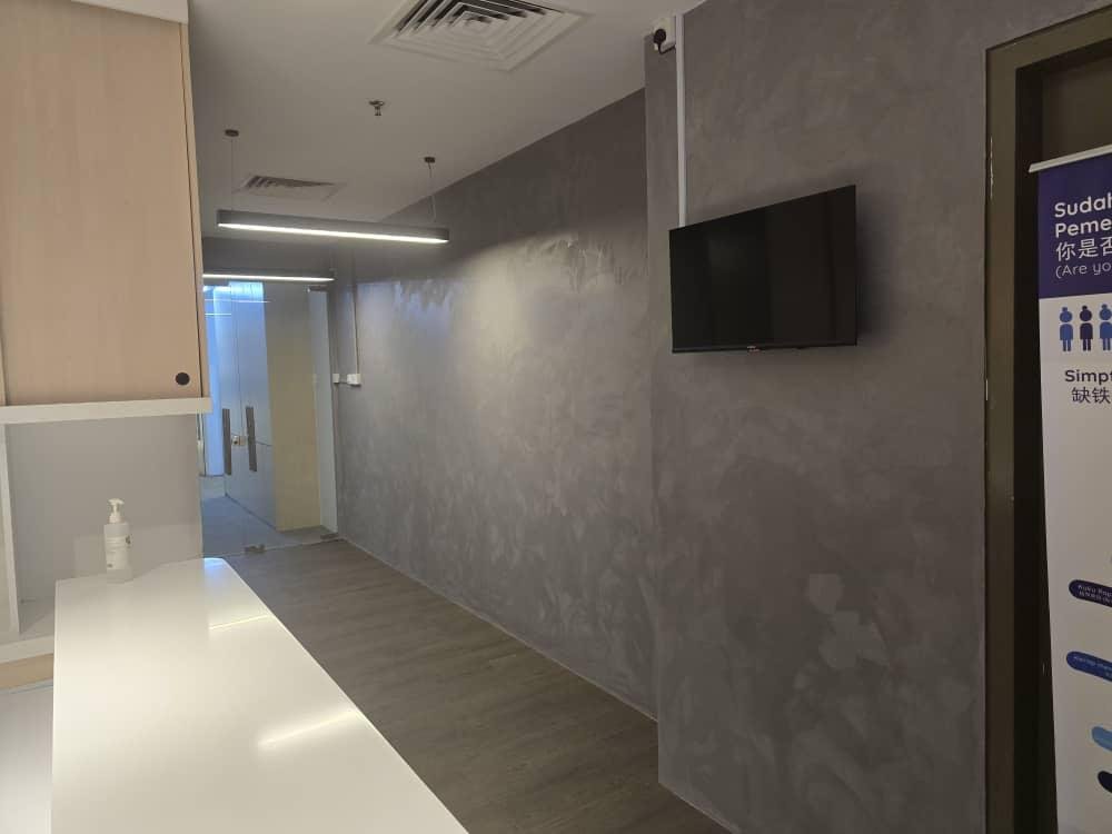 KLEM Clinics KL Eco City reception with bespoke grey microcement feature wall, reception counter and wall-mounted TV