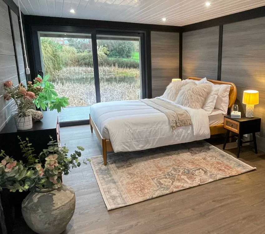 Guest annexe garden room with a bed, plants and large garden-view windows