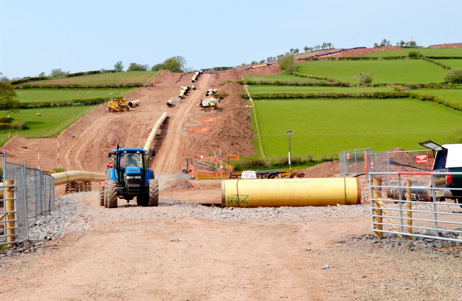 Curved pipeline working corridor across farmland with oilseed rape in the foreground