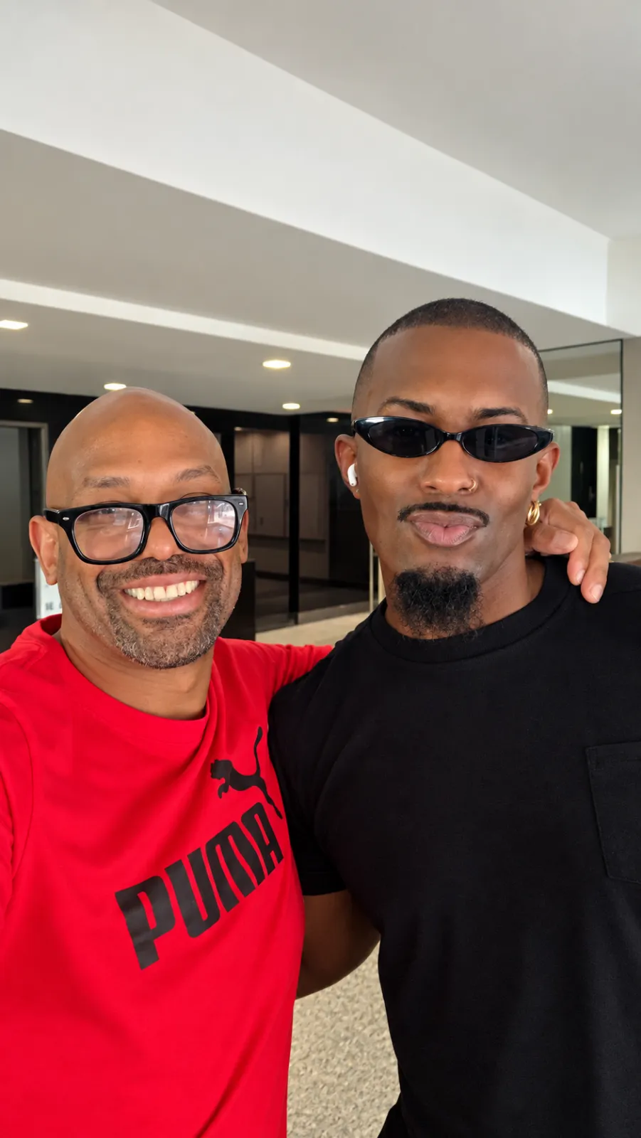Corey Wesley in a red shirt with his arm around a friend