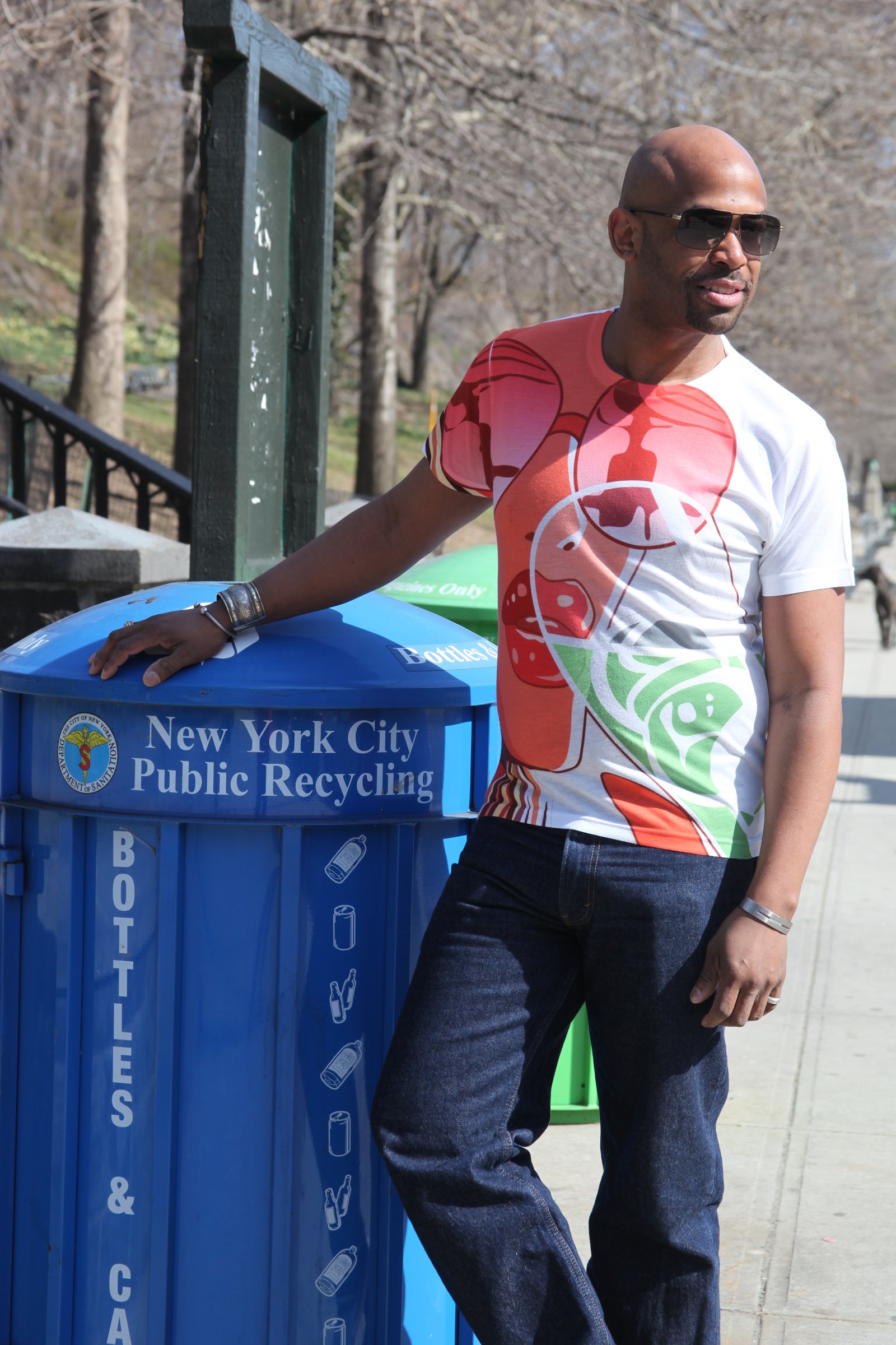 Corey Wesley beside a New York City recycling bin in a color-block graphic T-shirt