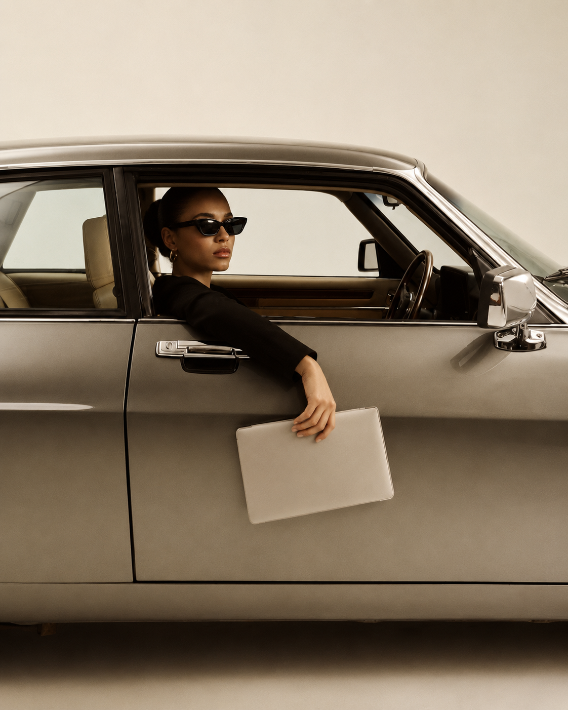 Woman using the Penny Bloom monthly budget spreadsheet on a laptop while parked in a classic car