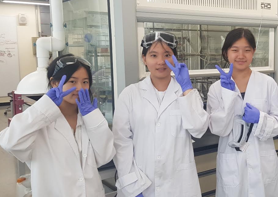 ConnectSTEM students wearing lab coats and safety goggles during a laboratory research experience at Seoul National University