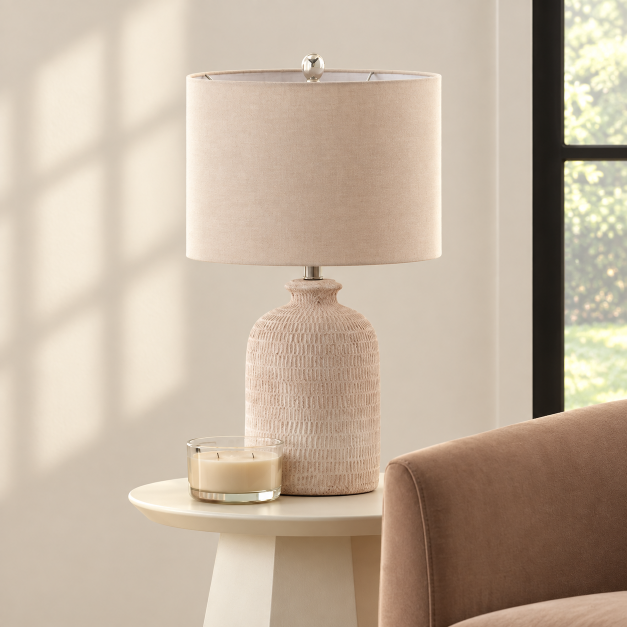 Textured pale ceramic table lamp with a linen drum shade on a neutral side table
