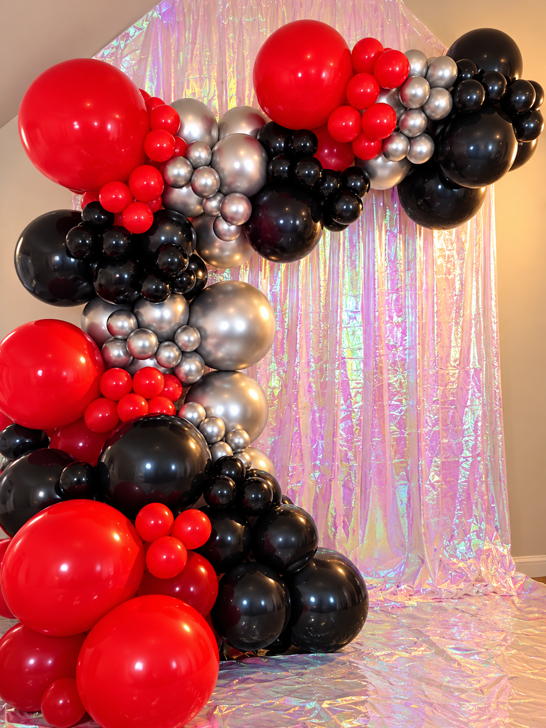 A 607 Balloon Craft artist adjusting a red and silver balloon garland at an event venue