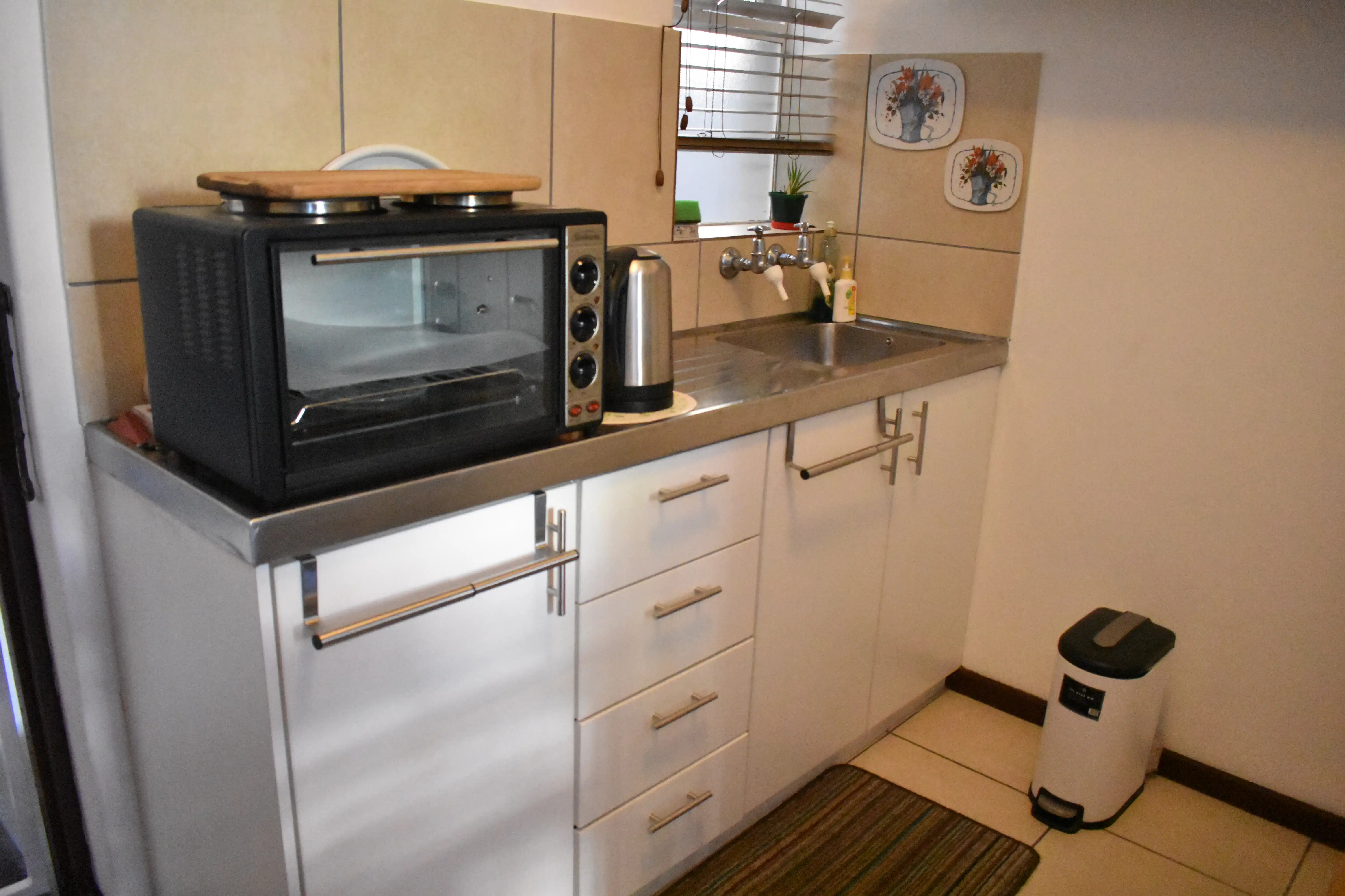 A kitchenette with a benchtop oven, kettle and sink in one of the Huis Uitsig apartments