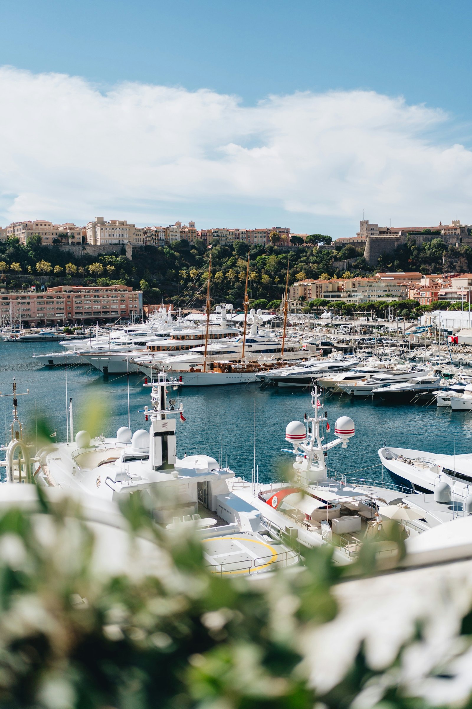 Monaco harbor at daytime with sailboat and superyachts, Rock of Monaco visible