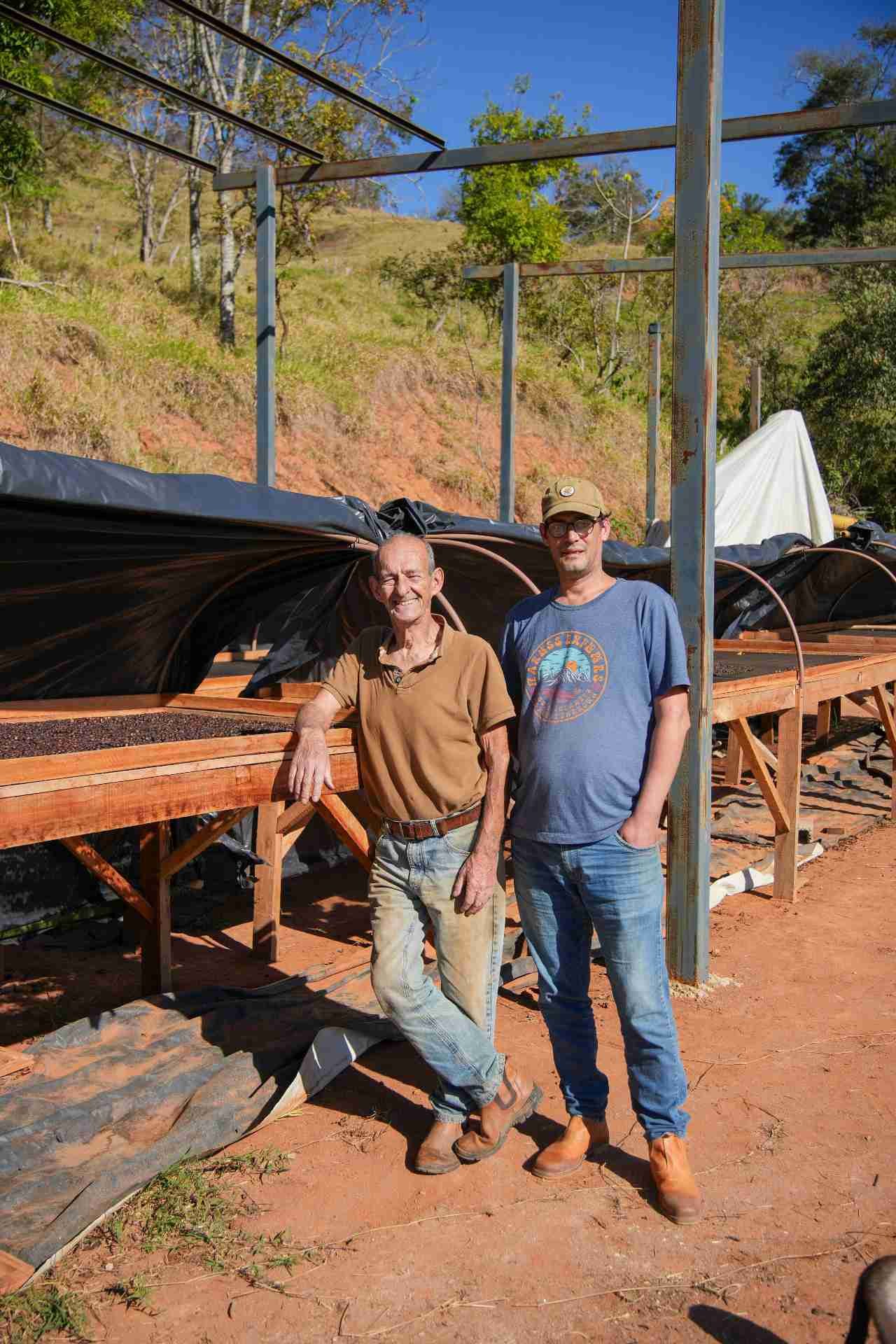 Pai e filho diante dos terreiros de secagem na terra vermelha