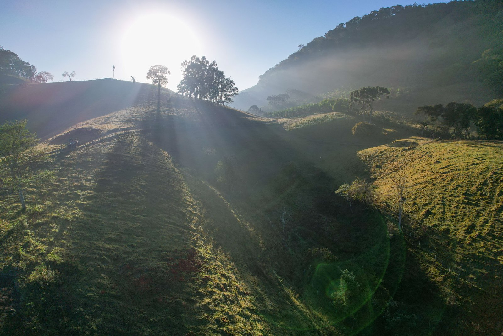Neblina da manhã e raios de sol sobre os morros