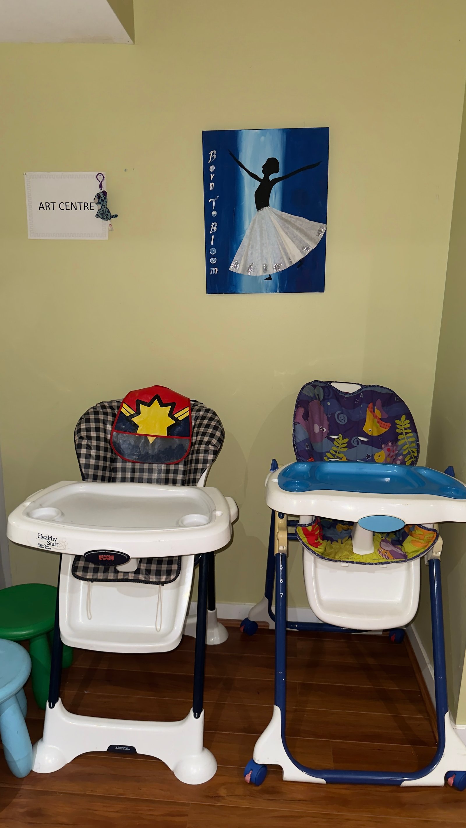 Two clean high chairs ready for mealtime beside the art centre wall