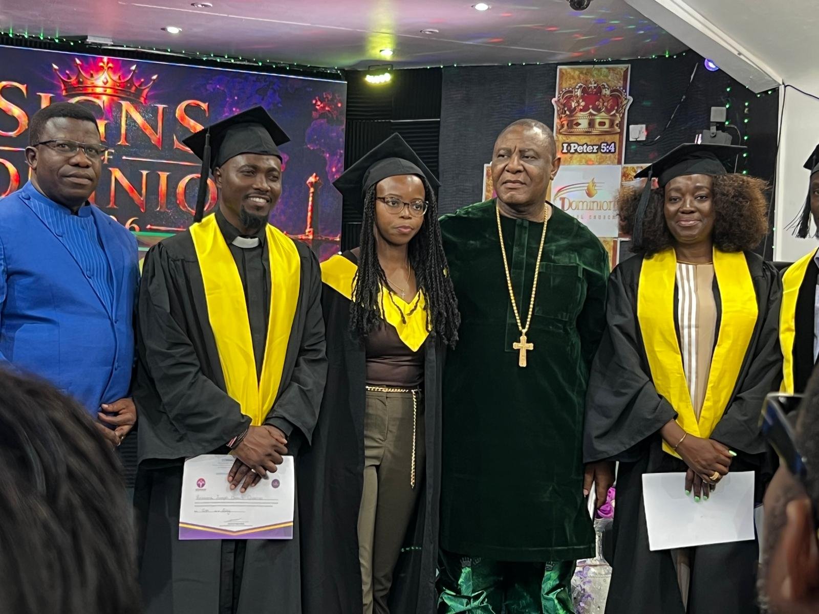 Joe Quarcoo in graduation robes holding his Certificate in Christian Leadership alongside other graduates and ceremony participants.