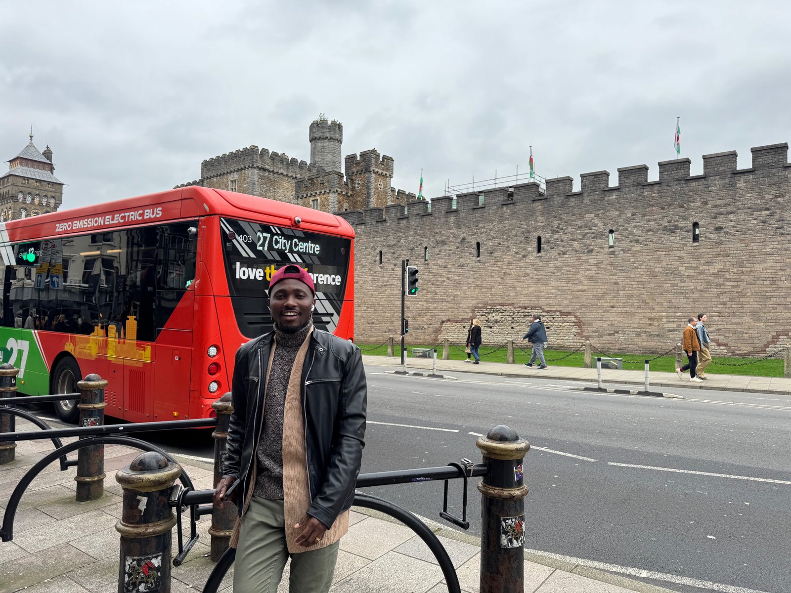 Joe Quarcoo beside a city bus within the historic centre of Cardiff.