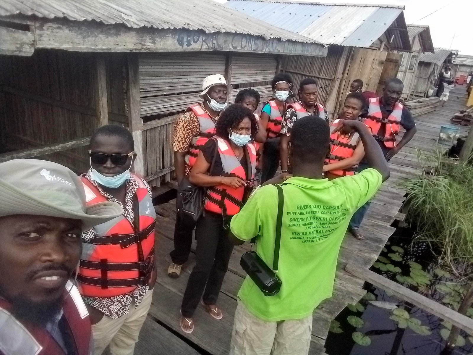 A collaborative field-reconnaissance team walking through a waterside settlement.