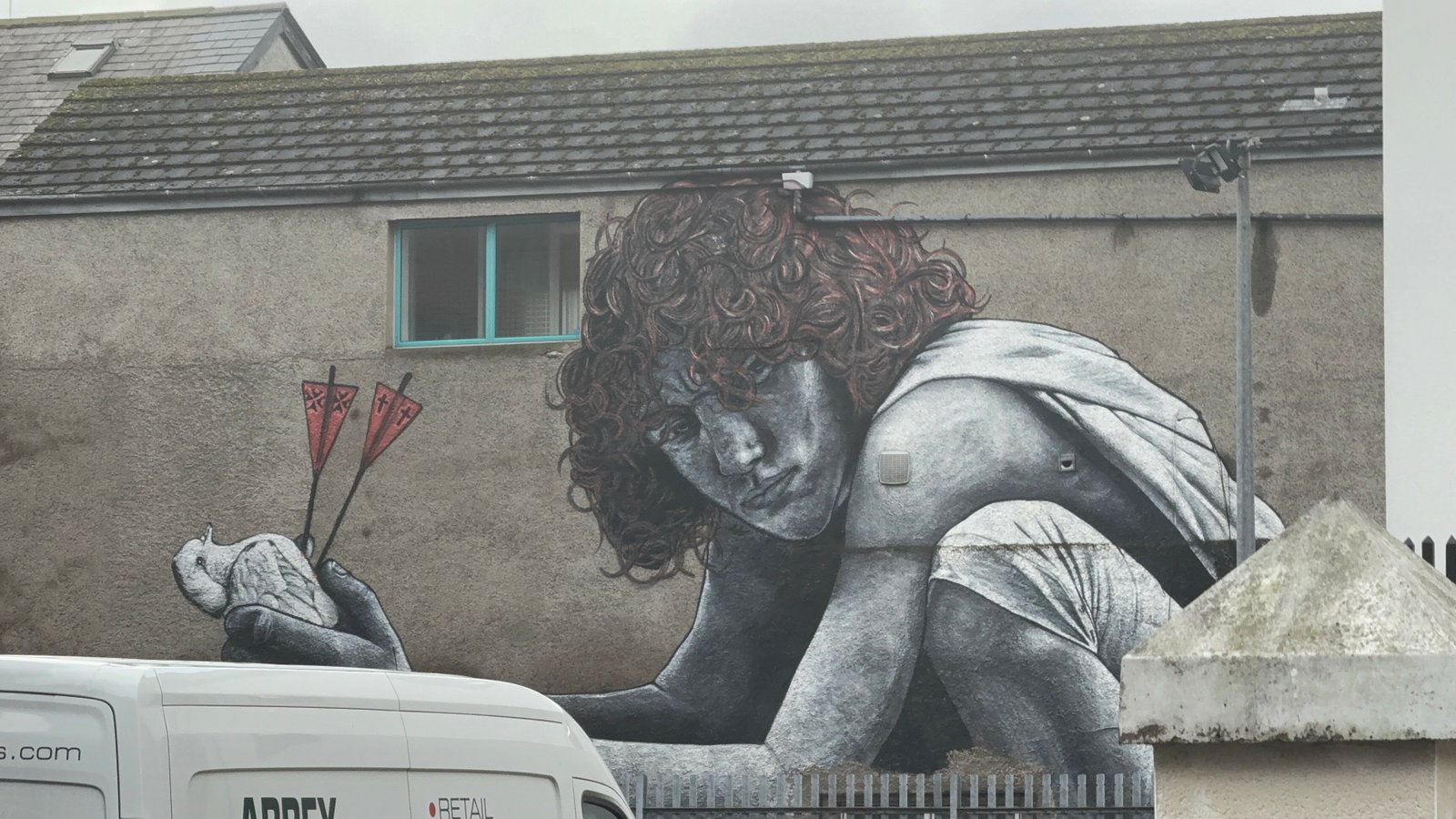 Large figurative mural painted on the side of a building in a UK neighbourhood.