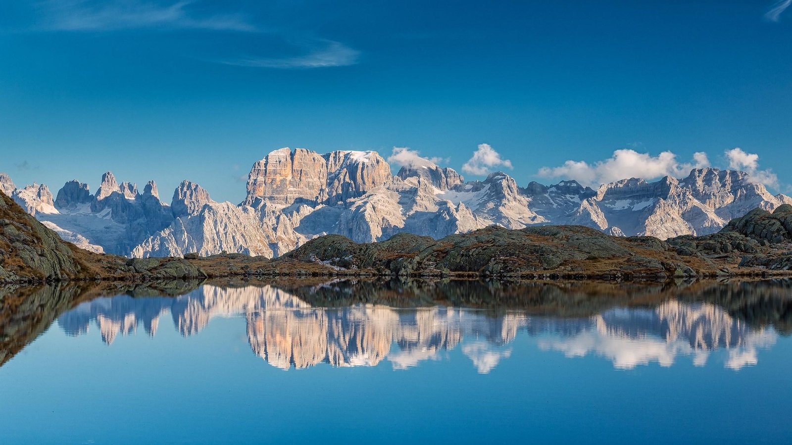 Snow-capped Brenta Dolomites reflected in an alpine lake in Trentino