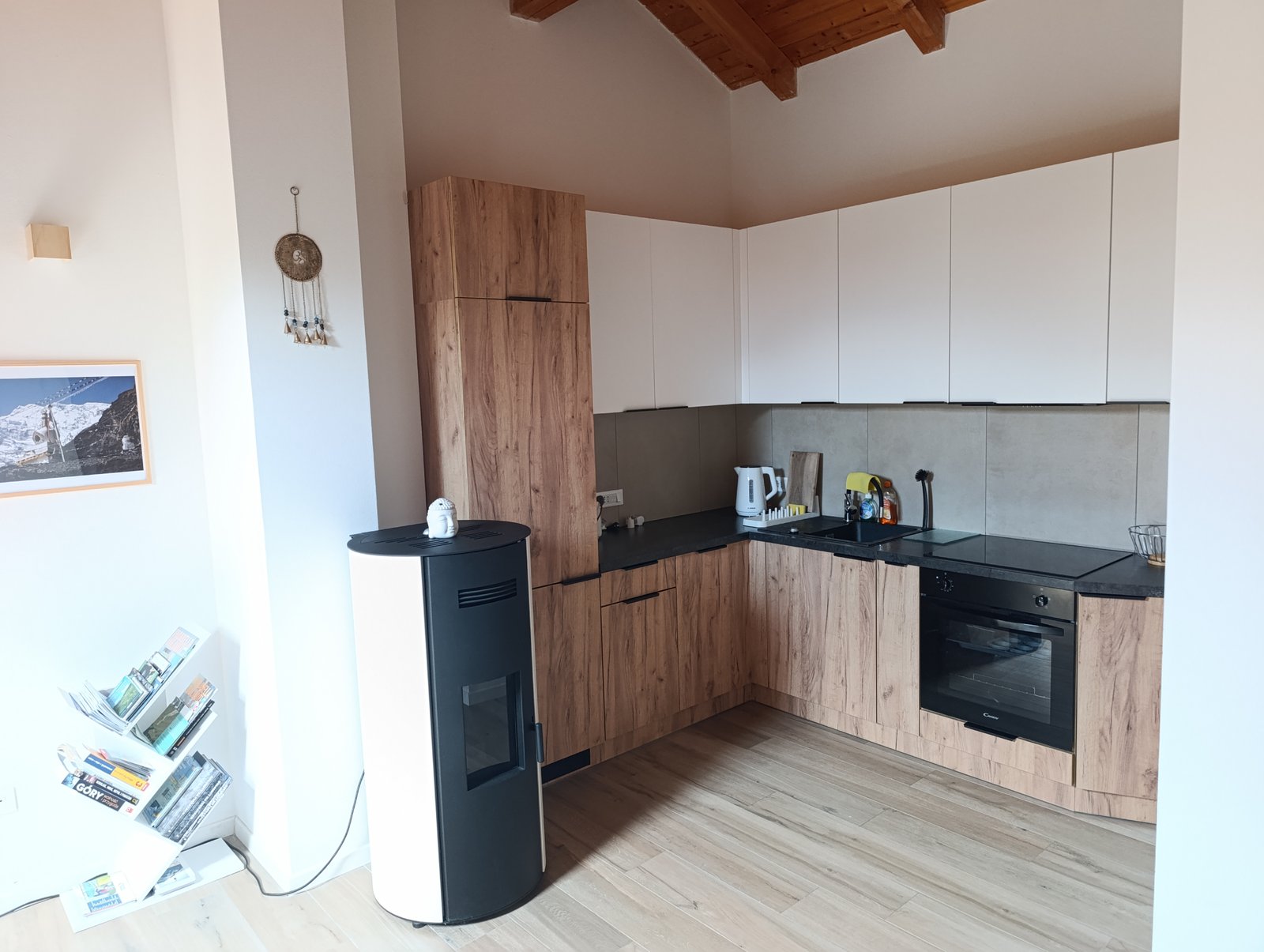 Modern fitted kitchen with wood cabinetry, white upper cabinets and black countertops