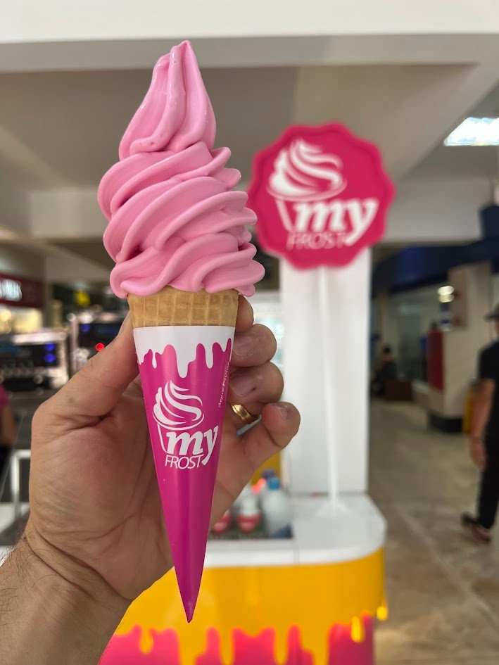 Fachada moderna de uma loja My Frost Sorveterias com iluminação vibrante e clientes desfrutando de sorvetes.