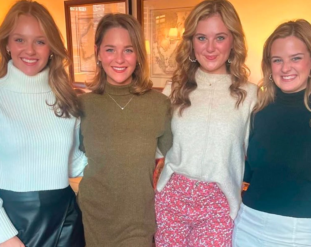 Four women in casual sweaters at indoor event with warm lighting
