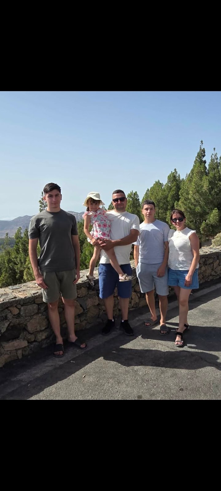 The Chaikivskyi family — parents with their three children, standing together by a stone wall in the mountains