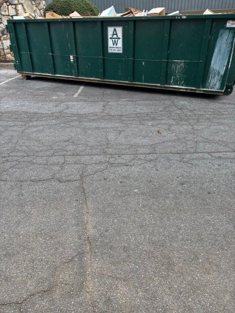 Large green commercial dumpster filled with office debris and furniture during a major commercial cleanout