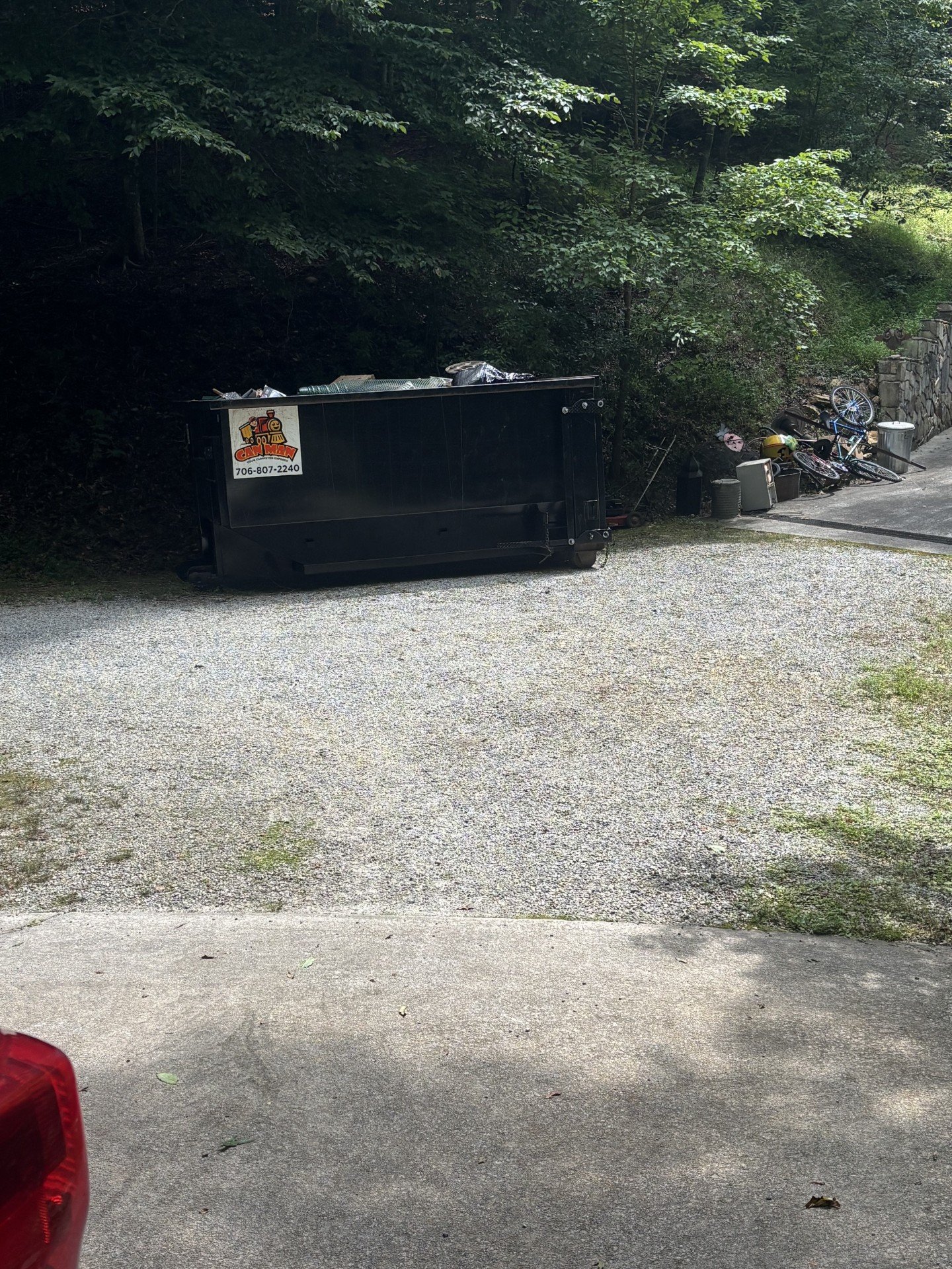Black dumpster loaded with junk removal debris with North Georgia Rapid Removal logo, bikes and items on the side