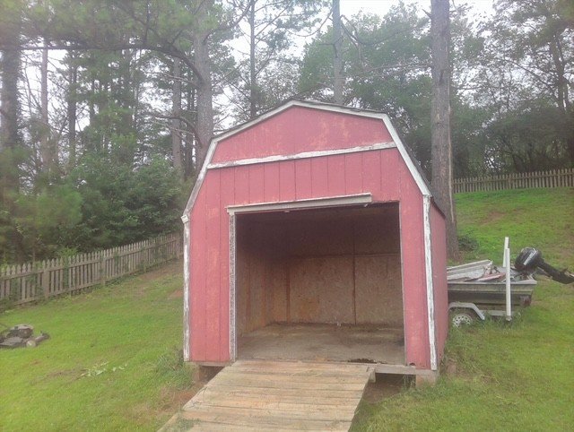 Red barn-style shed before demolition