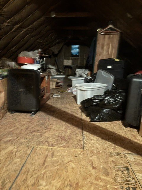 Attic space filled with junk, storage items, and miscellaneous boxes