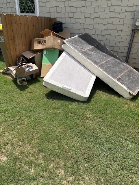 Backyard junk pile — boxes, mattresses, and debris before removal