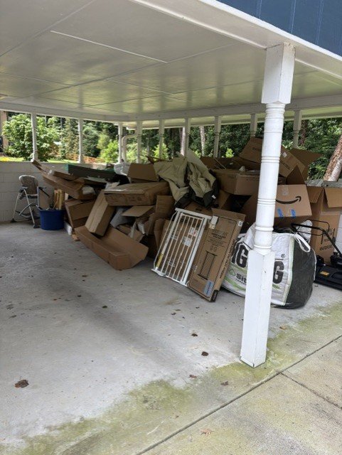 Carport with furniture and junk piled up before removal