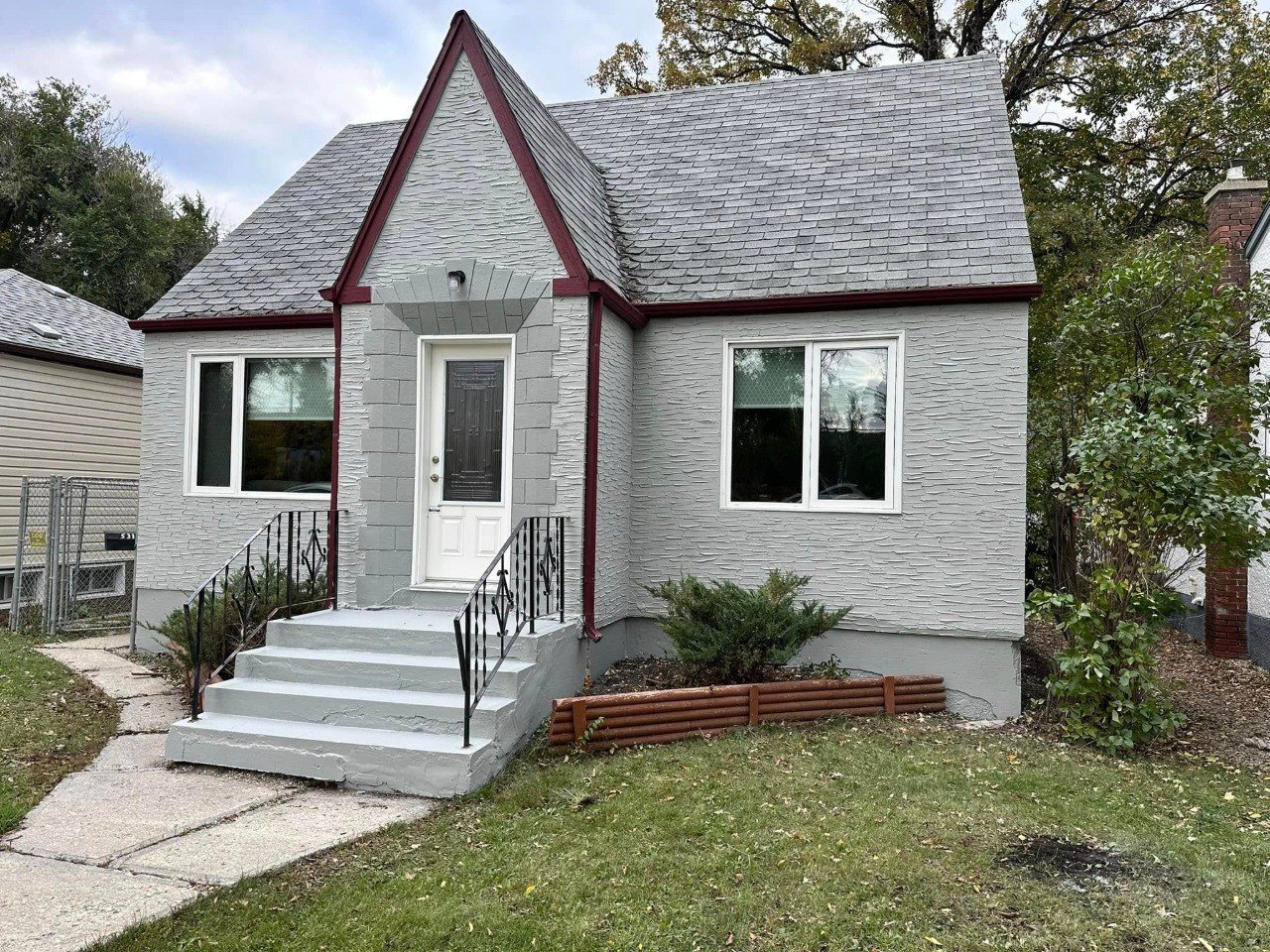 Small gray house with red trim and a new coat of paint