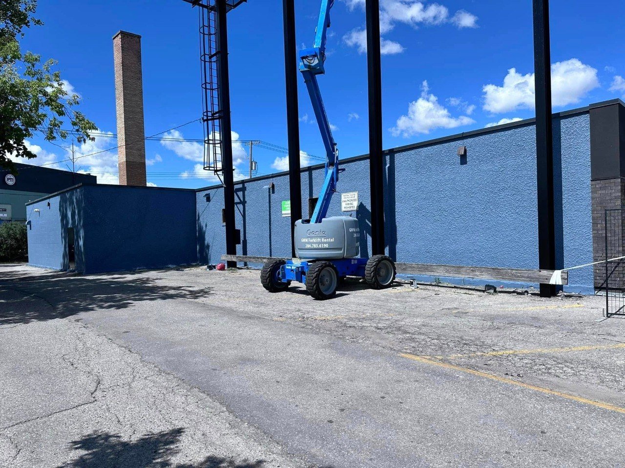 Boom lift beside an industrial building being painted