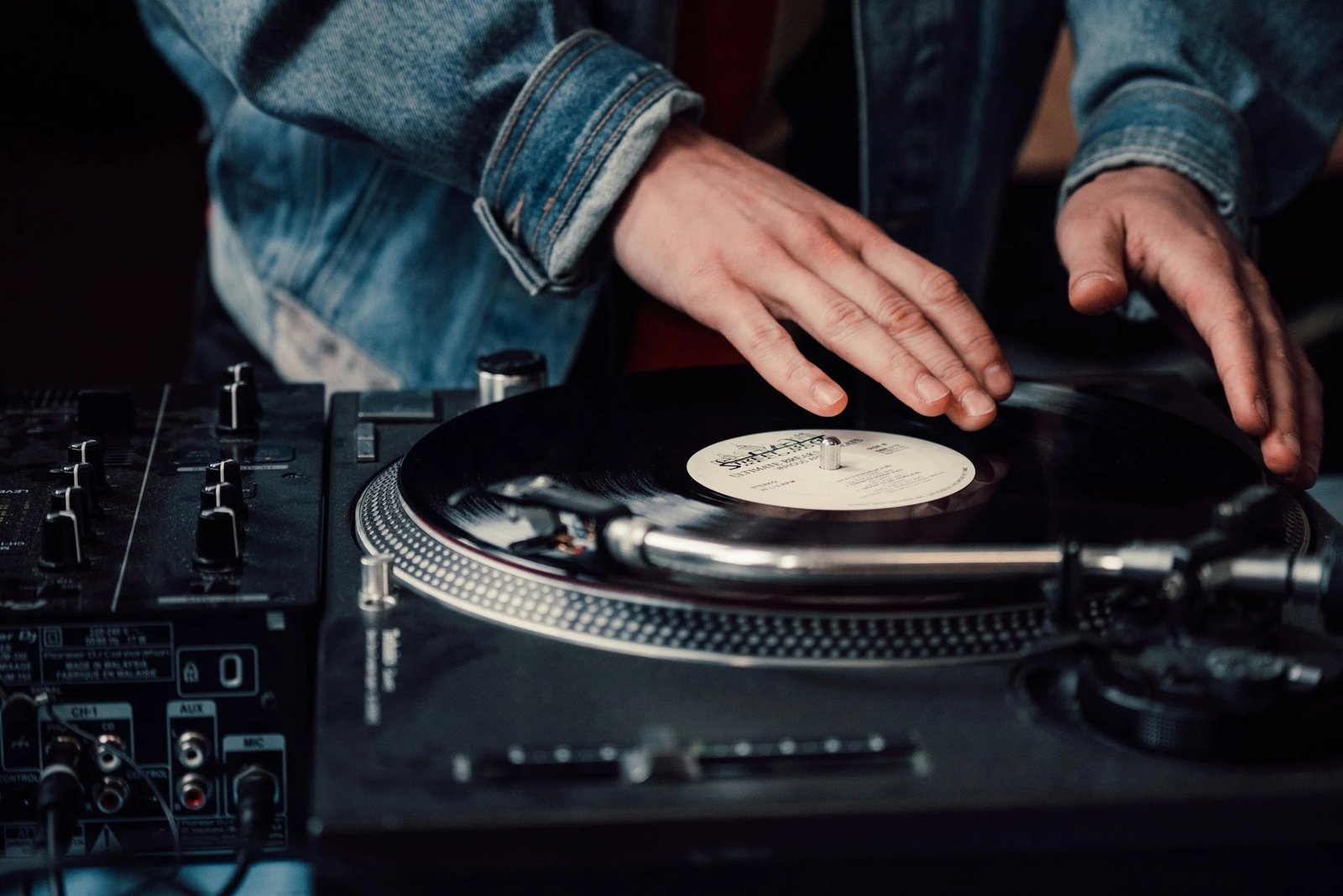 Portrait of Deejay Dawg beside his turntable setup under a copper rim light