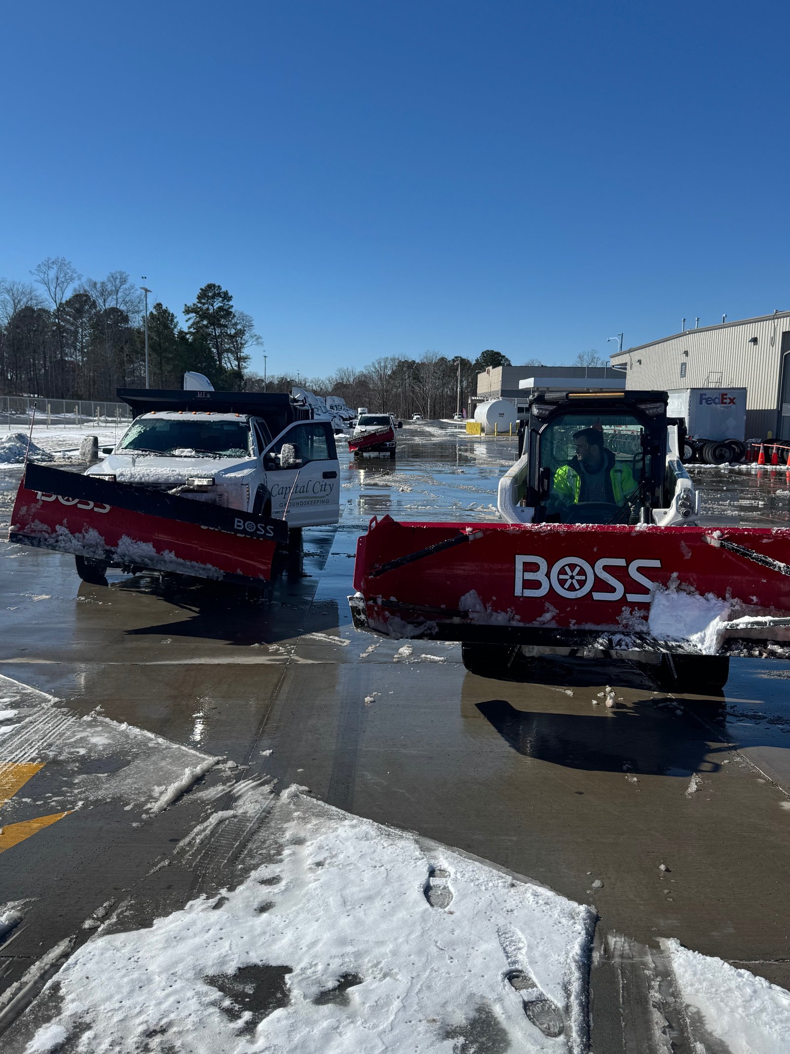 Snow plow and de-icing crew clearing a commercial parking lot and sidewalks during a North Carolina winter storm