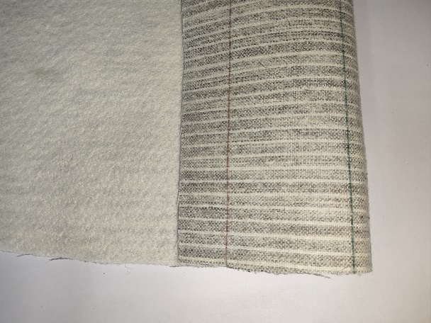 Economy grade needle-punched polyester felt roll in snow white and grey tones on a workbench