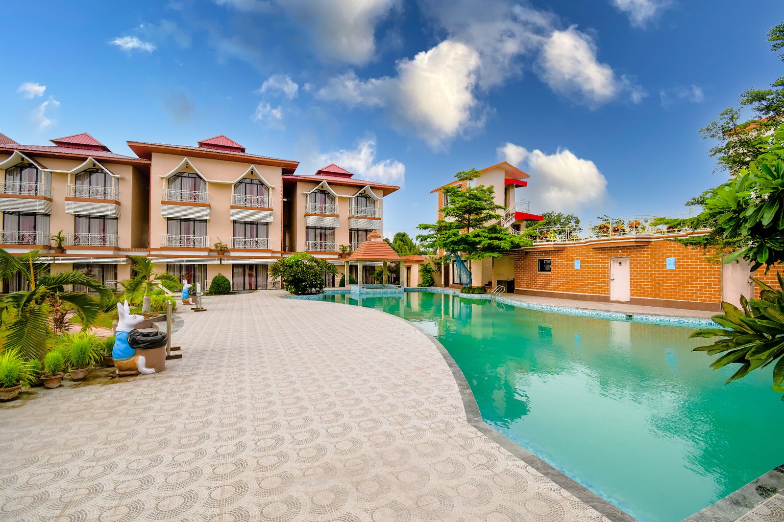 RRK Resort exterior with beige and orange buildings, red roofs, turquoise pool, and landscaped grounds