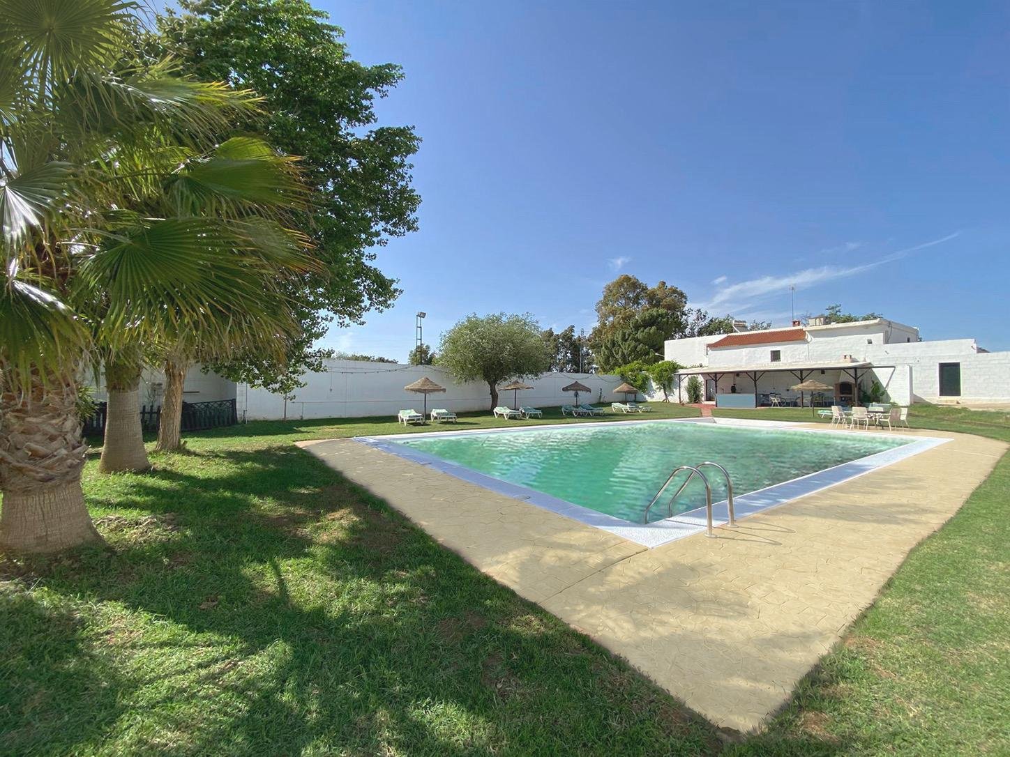 Pool and garden of Cortijo La Vega in Bobadilla under a blue sky
