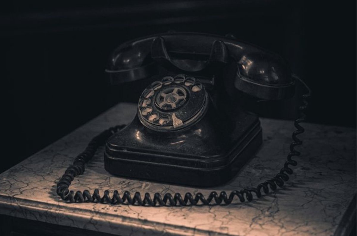 Telefono d'epoca in bachelite nera su tavolo di legno rustico