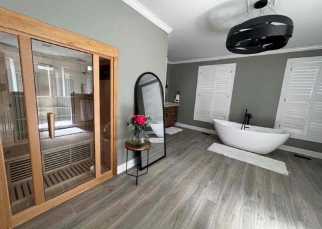 Contemporary bathroom with wood sauna, white soaking tub, gray walls, and modern fixtures