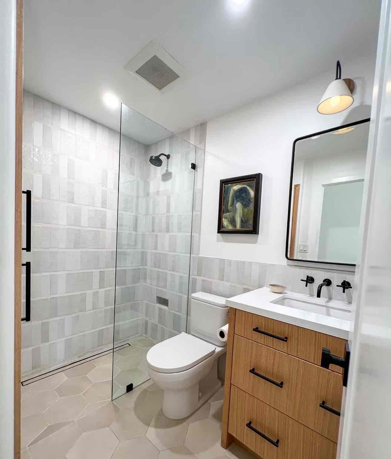 Contemporary bathroom with marble tile walls, built-in bench seating, black fixtures, and geometric floor tile