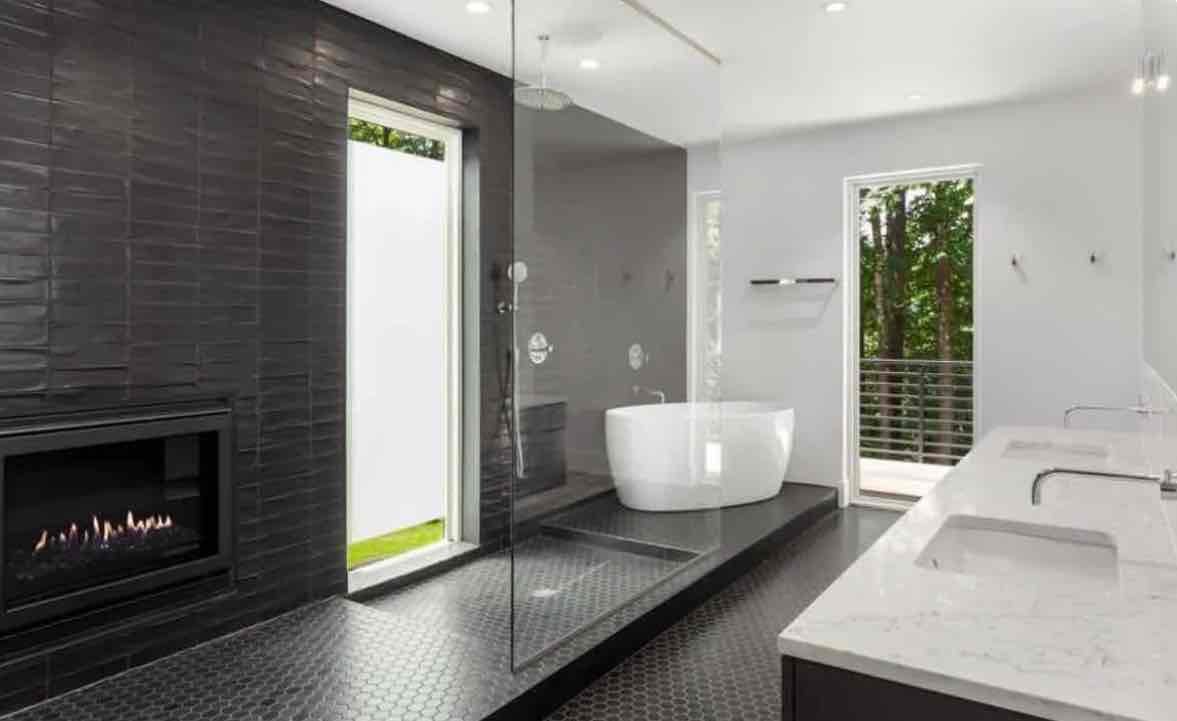 Contemporary luxury bathroom with marble tile walls, white soaking tub, black fixtures