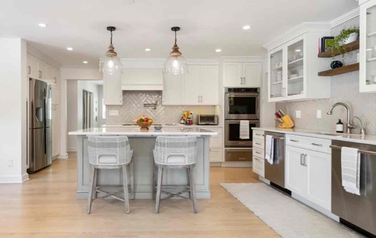 Luxury white kitchen with large island, brass fixtures, geometric floor pattern, and elegant pendant lighting