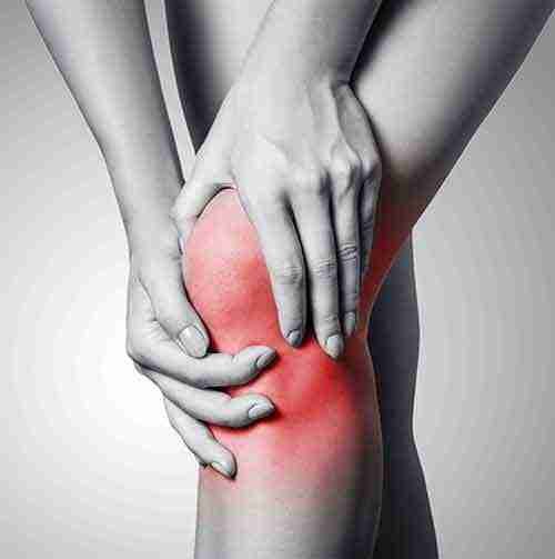 Close-up of a person holding their knee with red inflamed area indicating knee pain