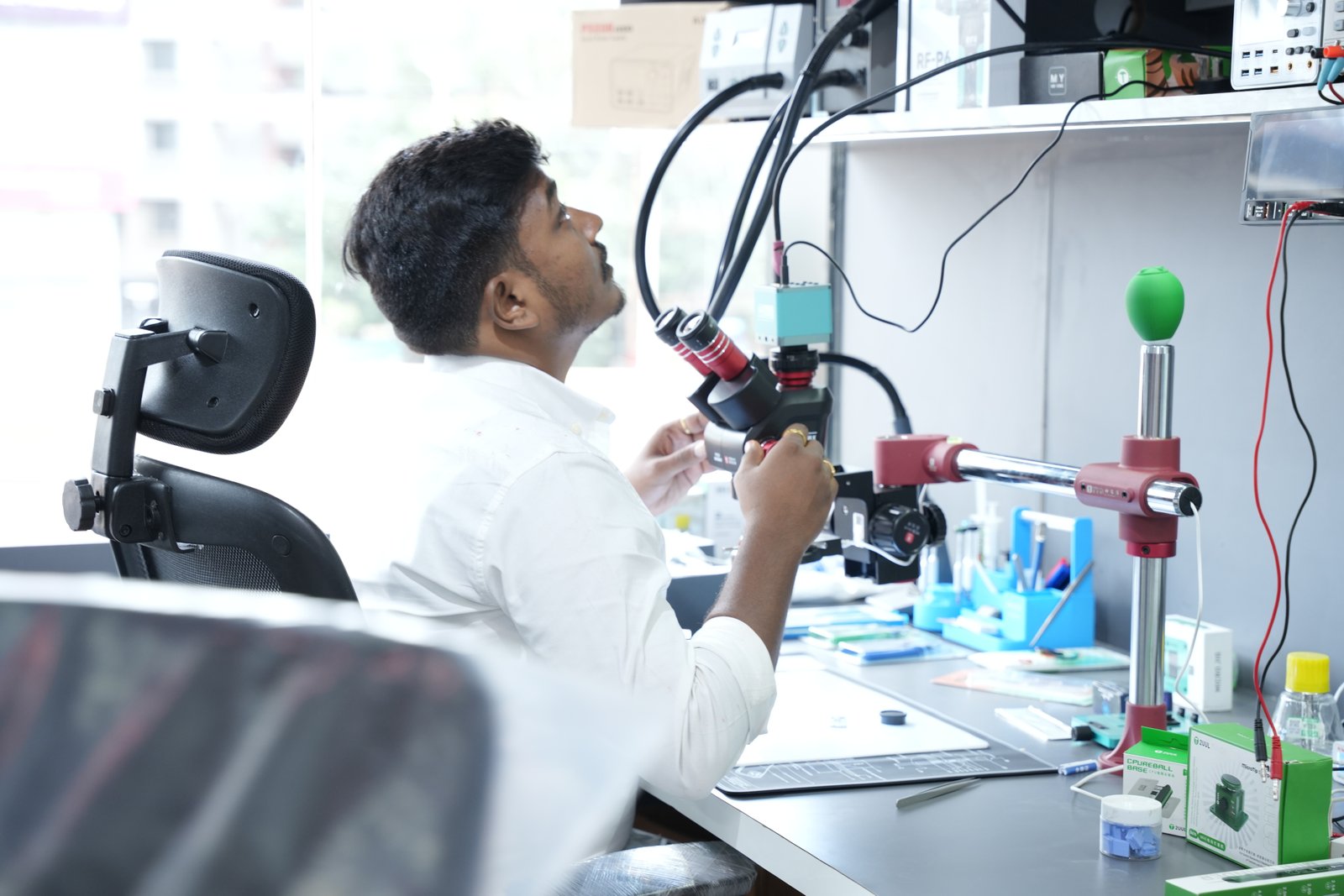 Technician working at a Mobile Fixit microscope bench with repair tools