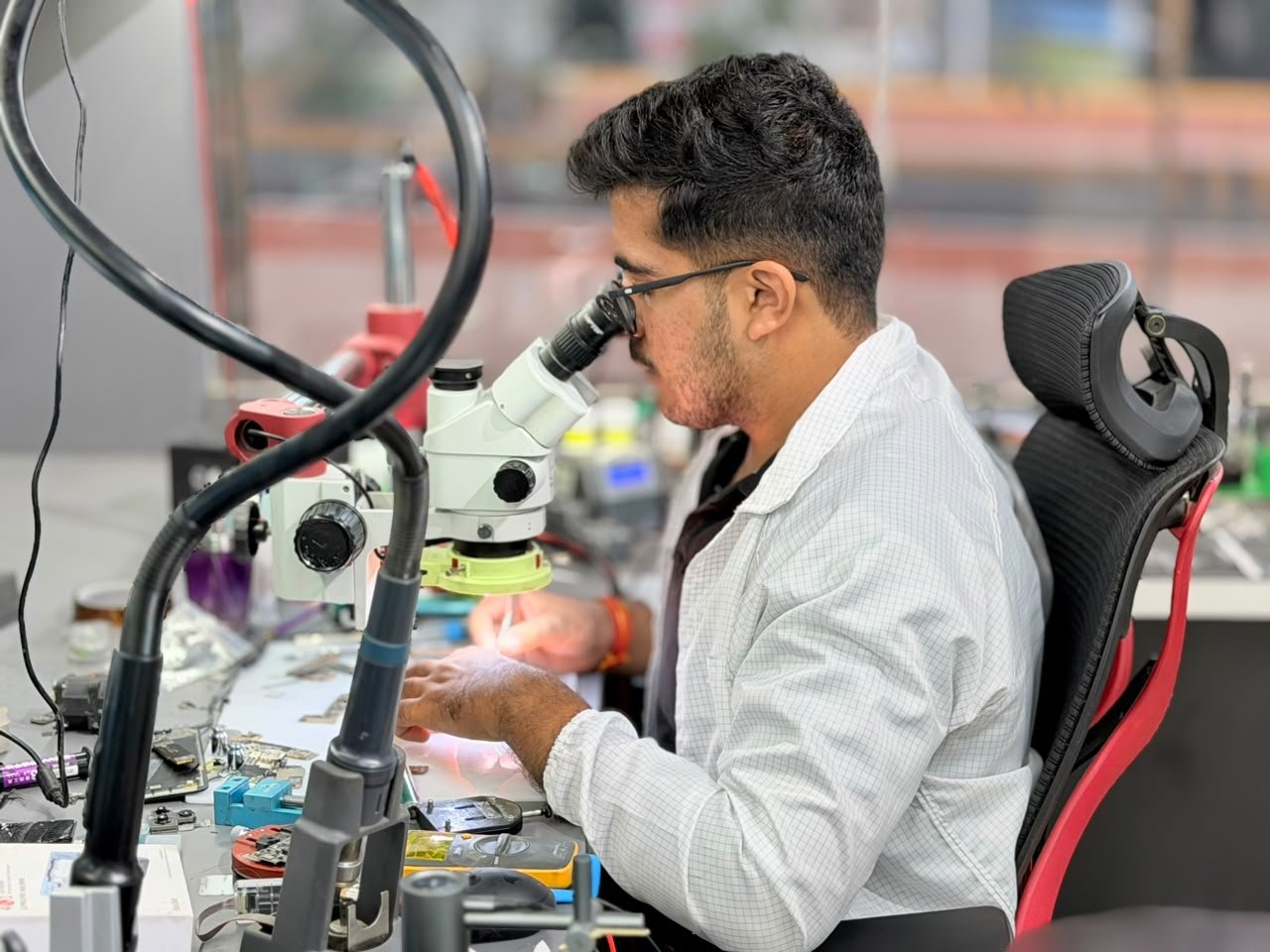 Mobile Fixit technician inspecting a phone board through a stereo microscope