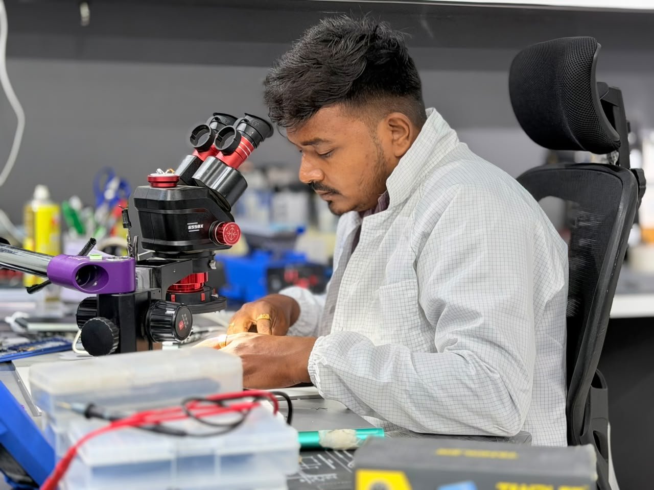 Mobile Fixit technician examining a device under a stereo microscope