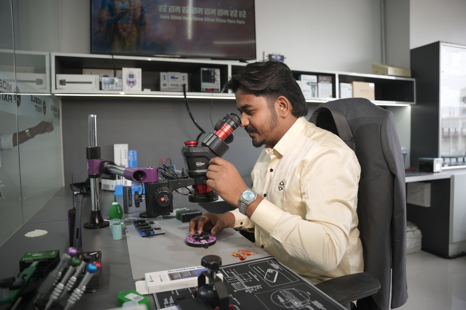 Mobile Fixit technician inspecting a phone board under a stereo microscope