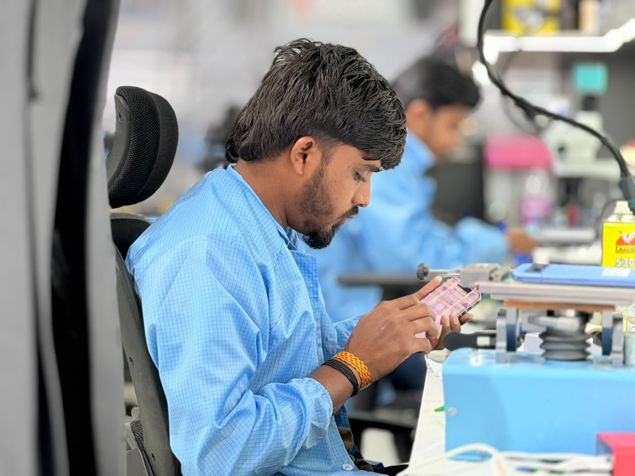 Mobile Fixit technician checking a phone display at the workshop bench
