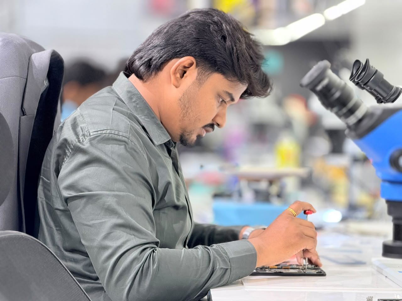 Mobile Fixit technician working on an opened phone at the repair bench